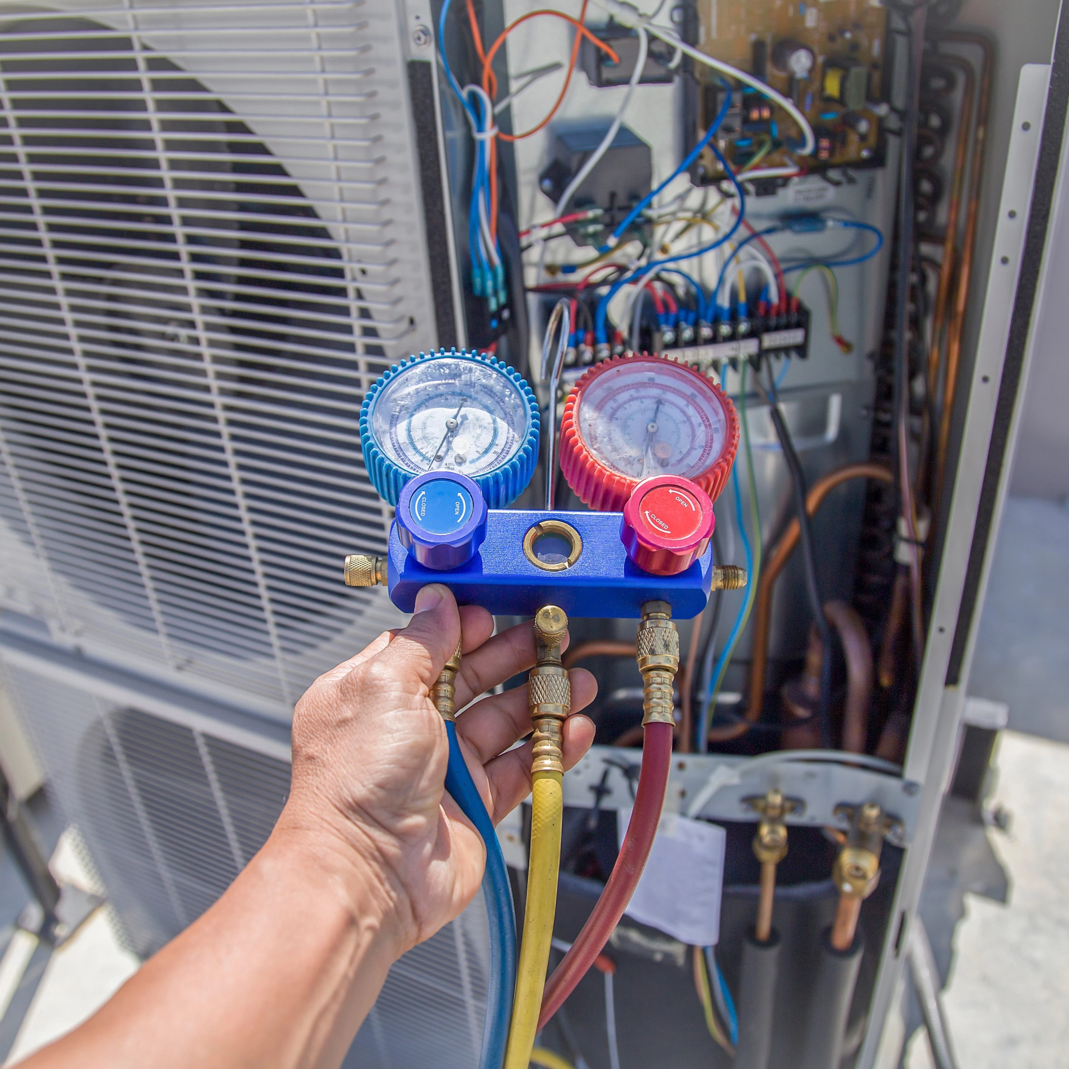 An Air Dynamics technician checking refrigerant levels on an HVAC unit during an AC installation in Broken Arrow.